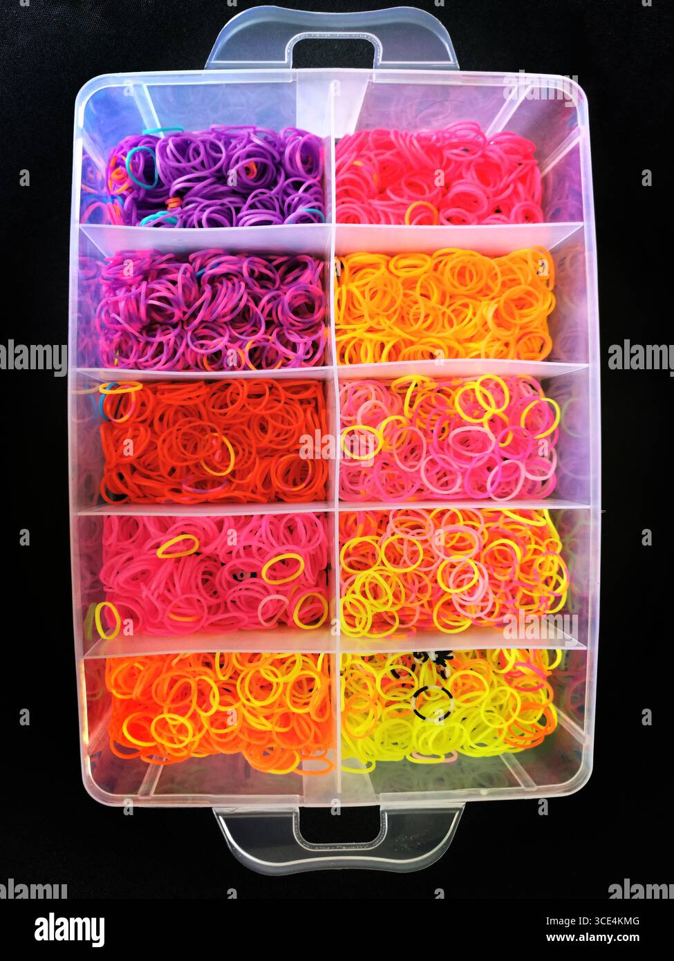 Numerose fasce in gomma sono disposte in modo ordinato in un contenitore trasparente che mostra colori vivaci come viola, rosa e arancione. Foto Stock