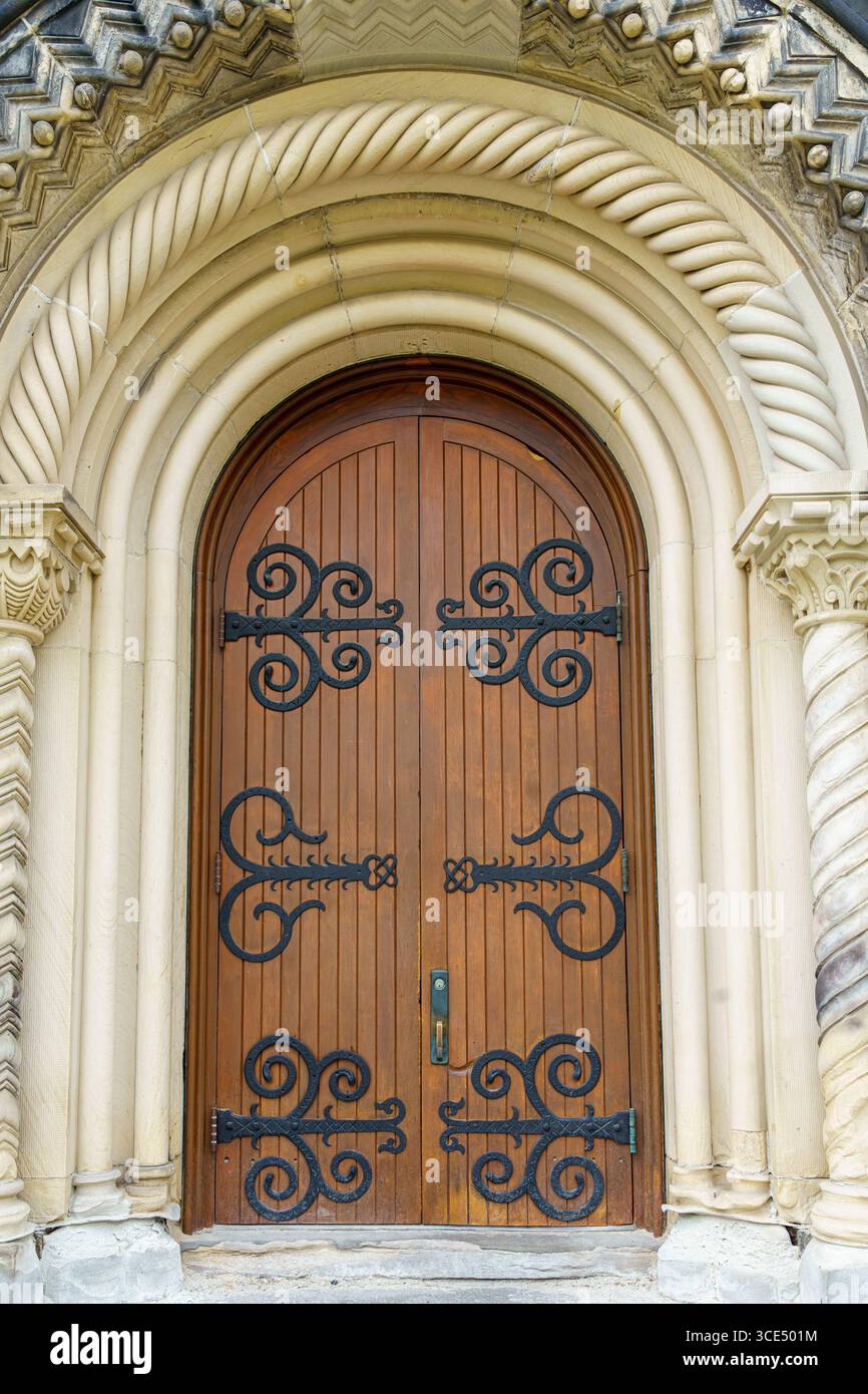 Porta ornata ad arco in legno con cerniere decorative in ferro battuto presso lo University College. Foto Stock