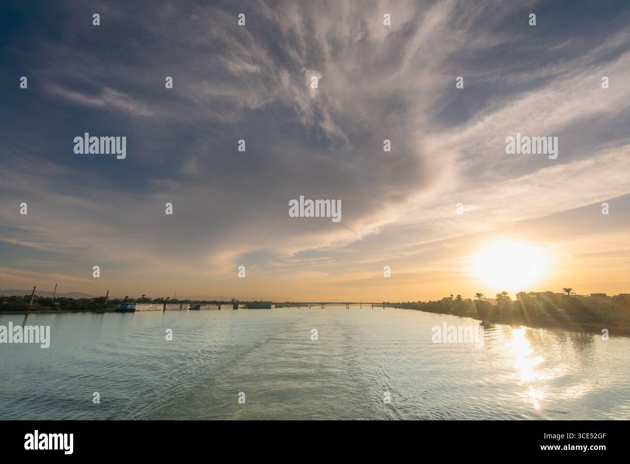 Splendida vista al tramonto di un ponte sul Nilo vicino al Tempio di Luxor in Egitto, con riflessi dorati sull'acqua e un cielo colorato. Foto Stock