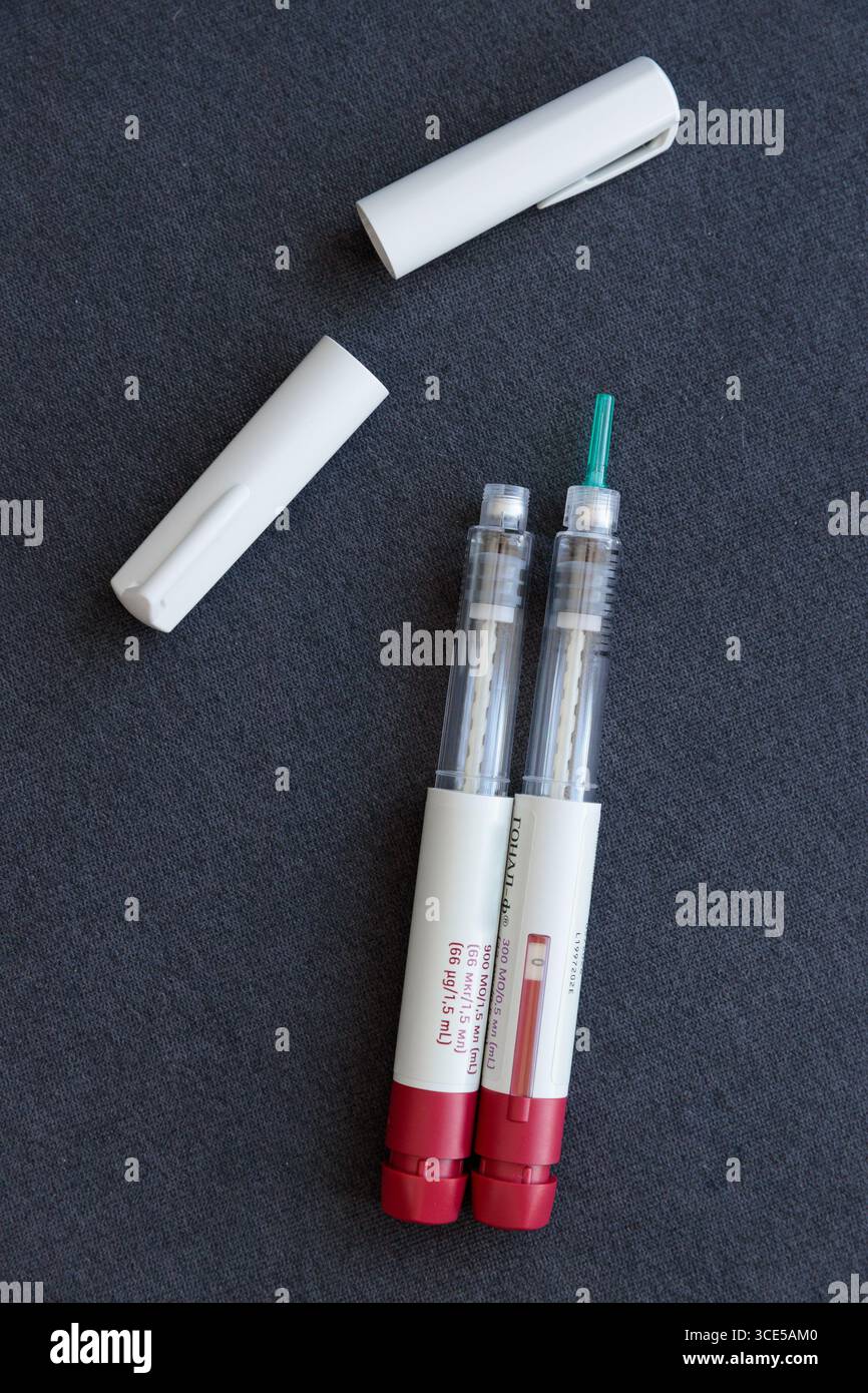 Questa immagine mostra due siringhe con cappucci protettivi posizionati su una superficie scura, sottolineando il ruolo fondamentale della manipolazione e della conservazione in sicurezza nel farmaco Foto Stock