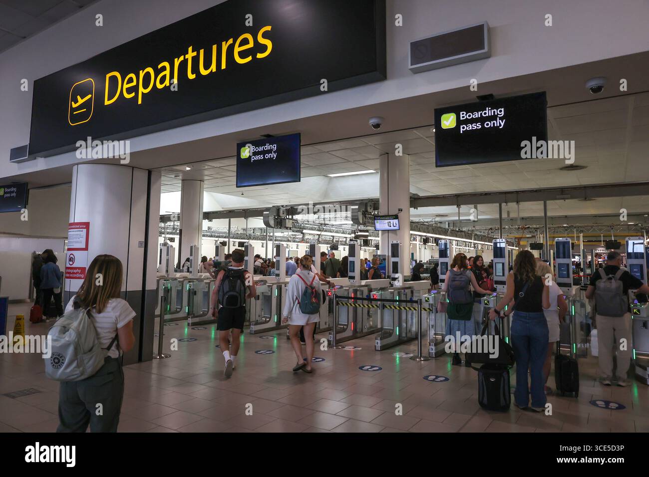 Partenze all'aeroporto di Gatwick, segui le indicazioni per la sala partenze dell'edificio del terminal nord dell'aeroporto di Gatwick e per i cancelli elettronici di sicurezza della carta d'imbarco Foto Stock