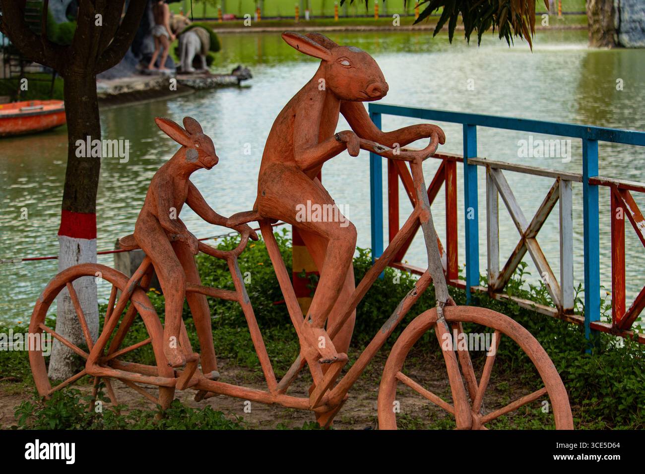 Statue creative di conigli che pedalano insieme lungo il lago nel Dream Holiday Park Foto Stock
