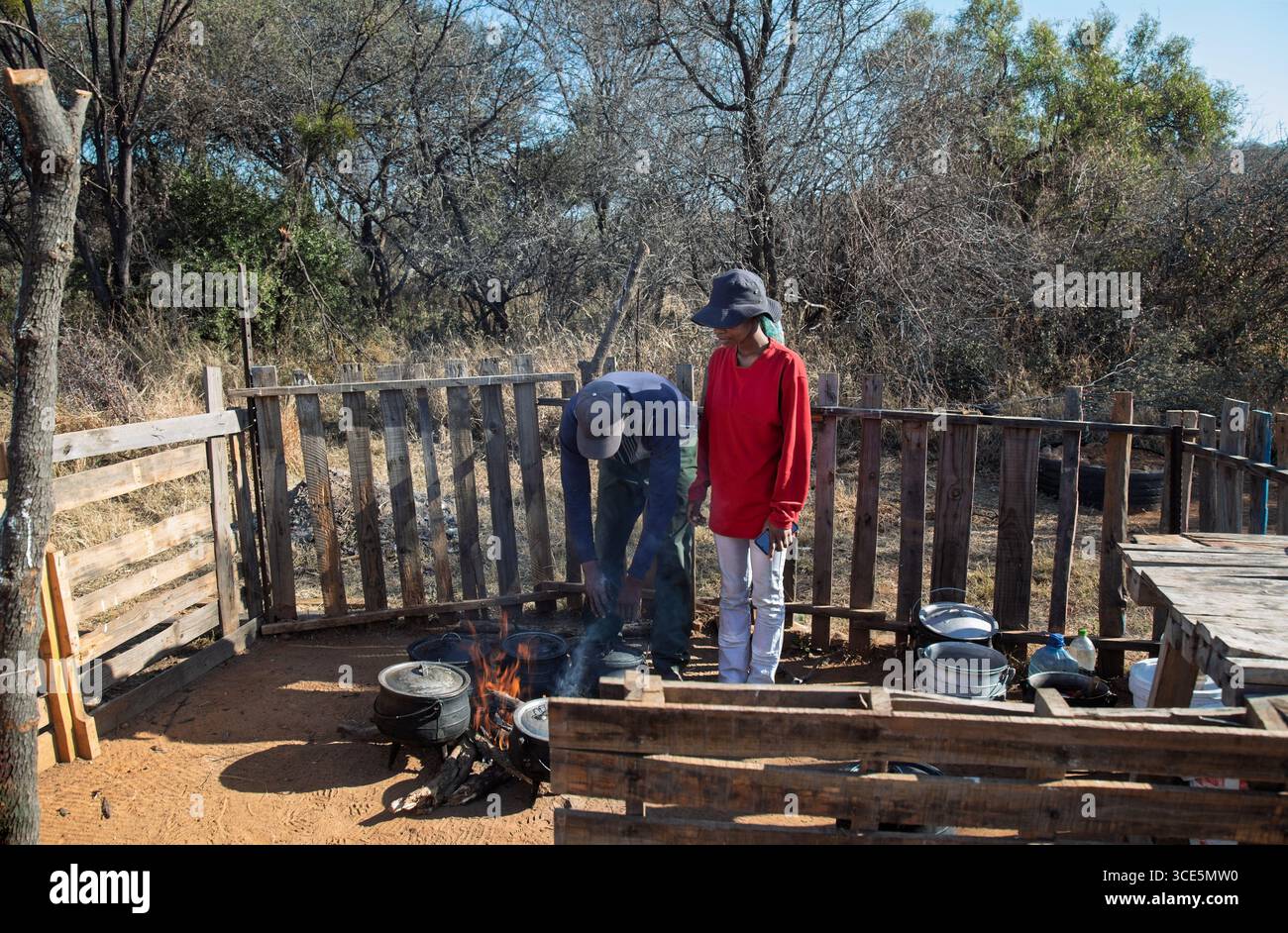 Cibo di strada africano, piccoli venditori ambulanti che cucinano cibo, calderone a tre zampe in recinzione chiusa sul lato della strada, Gaborone, Botswa Foto Stock