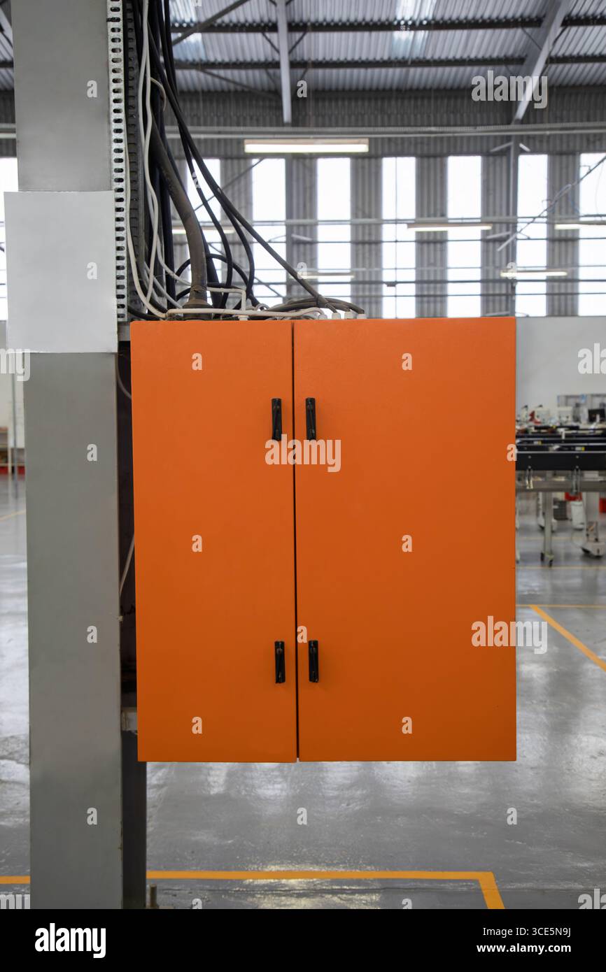 Armadio elettrico arancione usato come contenitori industriali , quadri elettrici , contenitori IP, scatola industriale arancione in fabbrica Foto Stock