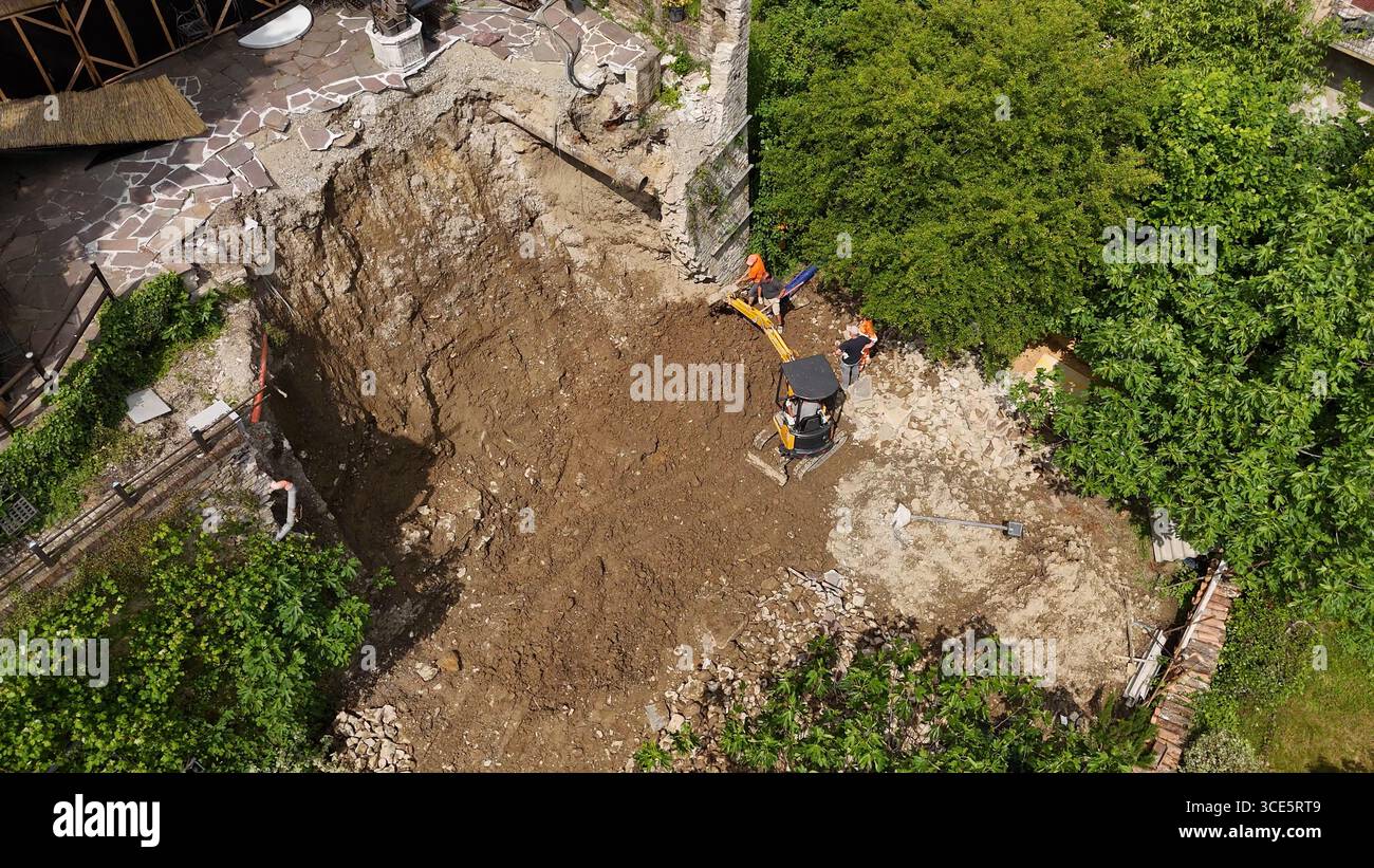 Castell'Arquato, Italia - 24 aprile 2025 Vista aerea di un trattore compatto con timone rotante collegato che elimina erbacce coltivate e erba densa Foto Stock