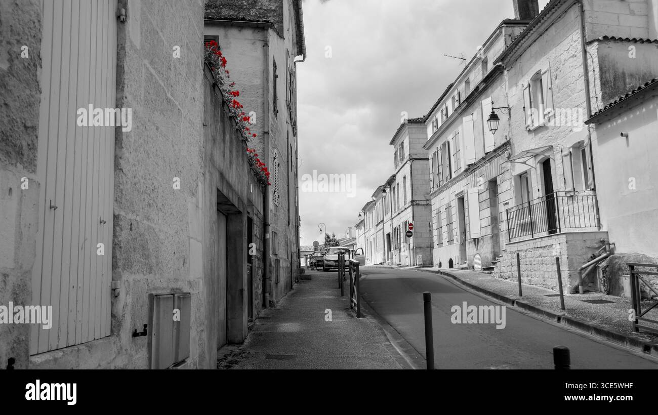 Studio in bianco e nero di una strada a Saintes, Francia, con accenti rossi selettivi: Scena urbana con prospettiva artistica Foto Stock