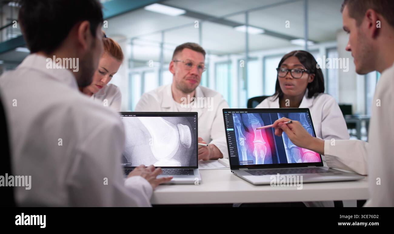 Radiologo che presenta i raggi X su un laptop a diversi gruppi di medici. Foto Stock