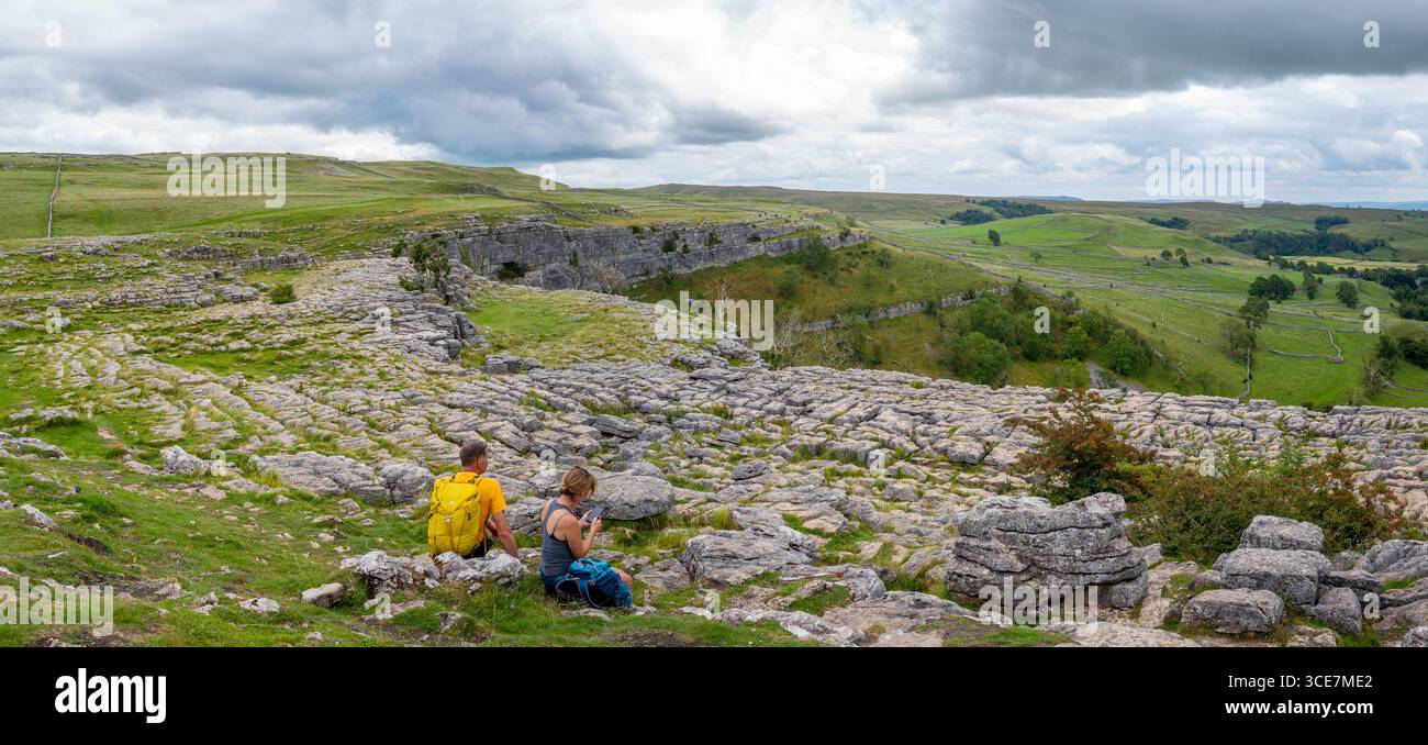 La coppia sedeva sulla cima di Malham Cove, Malham Cove, una cascata acida alta 70 metri a Malham e una popolare attrazione turistica nel North Yorkshire. Foto Stock