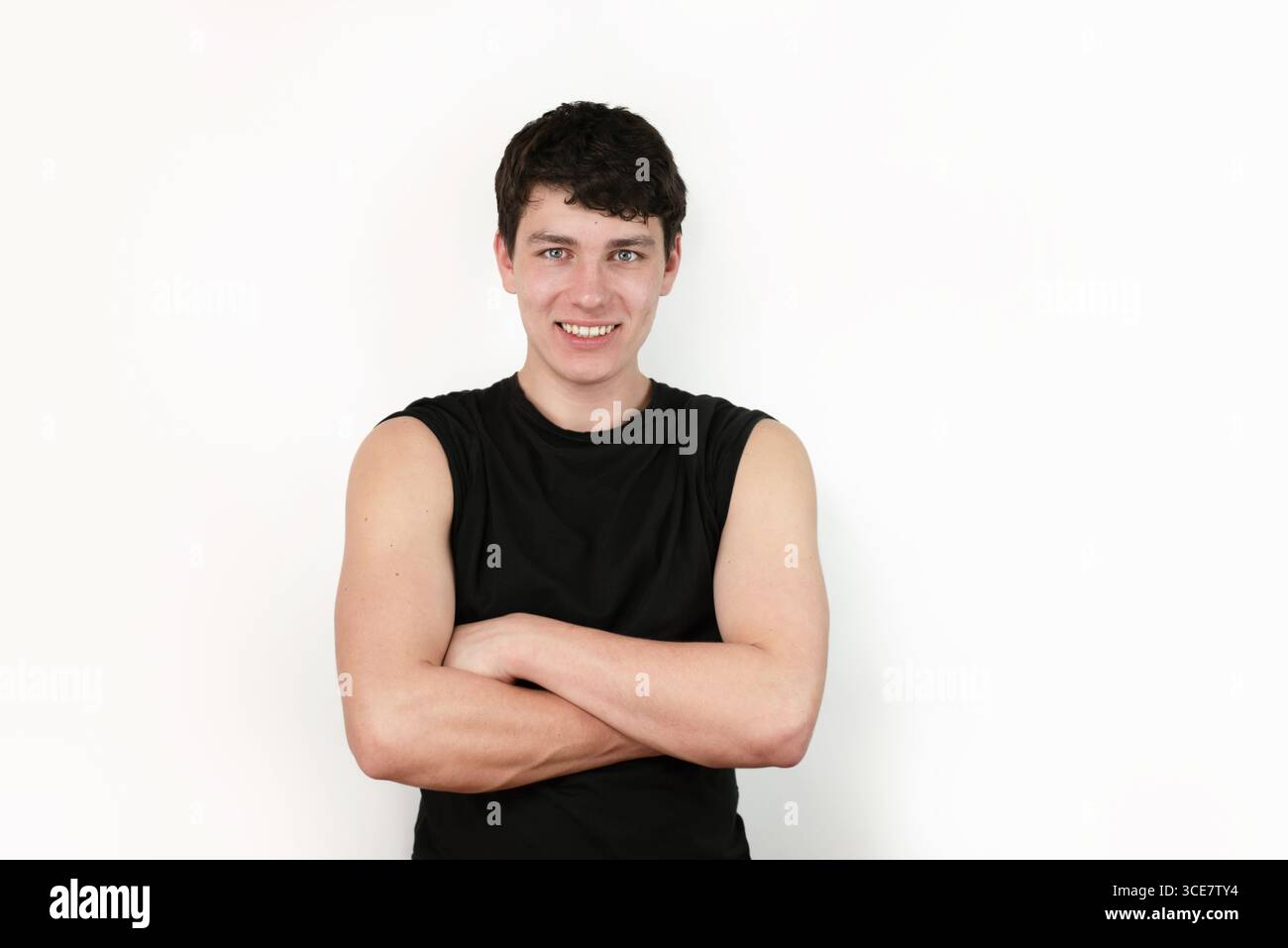 Un uomo sicuro di sé con un atteggiamento casual e un sorriso amichevole che indossa una camicia nera su sfondo bianco, sottolineando la sicurezza e la positività Foto Stock