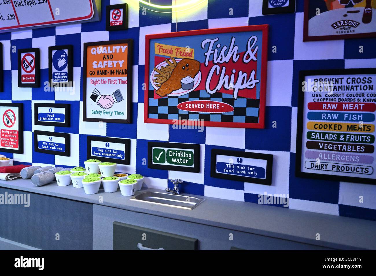 Insegne artistiche in feltro per l'igiene del cibo alla mostra d'arte Bourdon Street Chippy - Lucy Sparrow Foto Stock