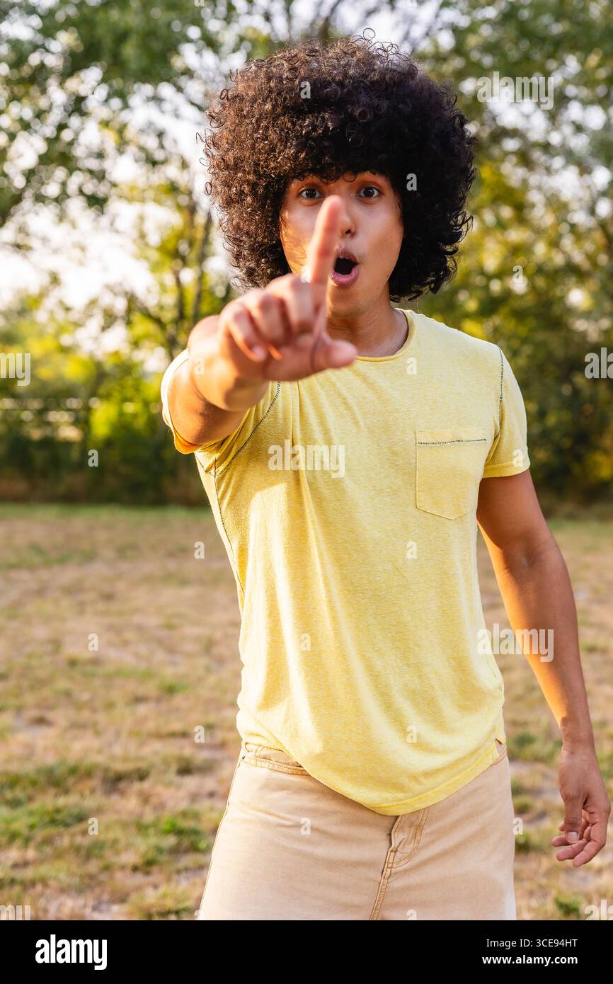 Giovane che punta il dito con un'espressione stupita in parco Foto Stock
