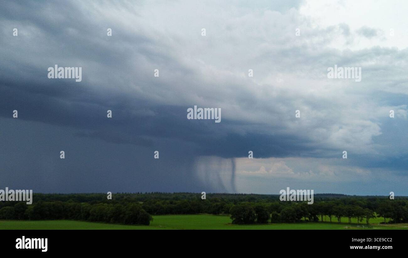 Pioggia, nuvole scure e un paesaggio con alberi Foto Stock