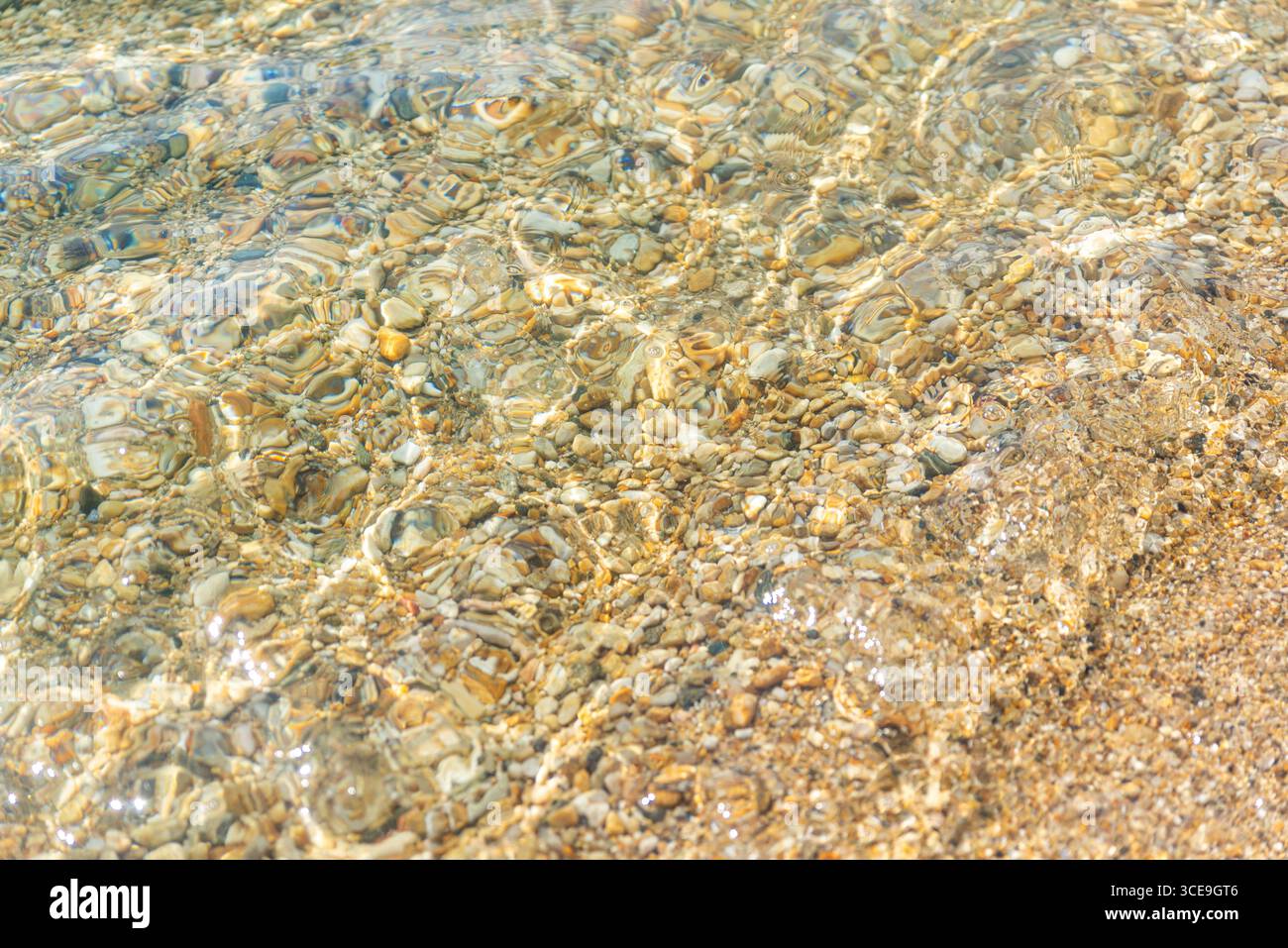 Primo piano di acque cristalline con piccoli ciottoli visibili sul fondo sabbioso Foto Stock