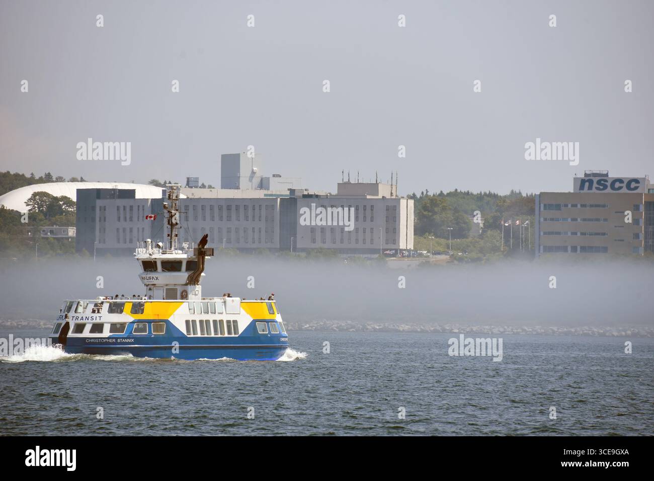 Halifax, Canada - 30 luglio 2025: Il traghetto Dartmouth si dirige verso Halifax in una foschia di nebbia. Il Nova Scotia Community College si trova nel backgro Foto Stock