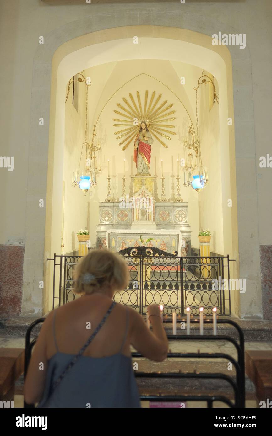 cappella del Sacro cuore di Gesù, donna offuscata che accende candele nella Cattedrale di Sant'Agata a Catania, Sicilia, Italia Foto Stock