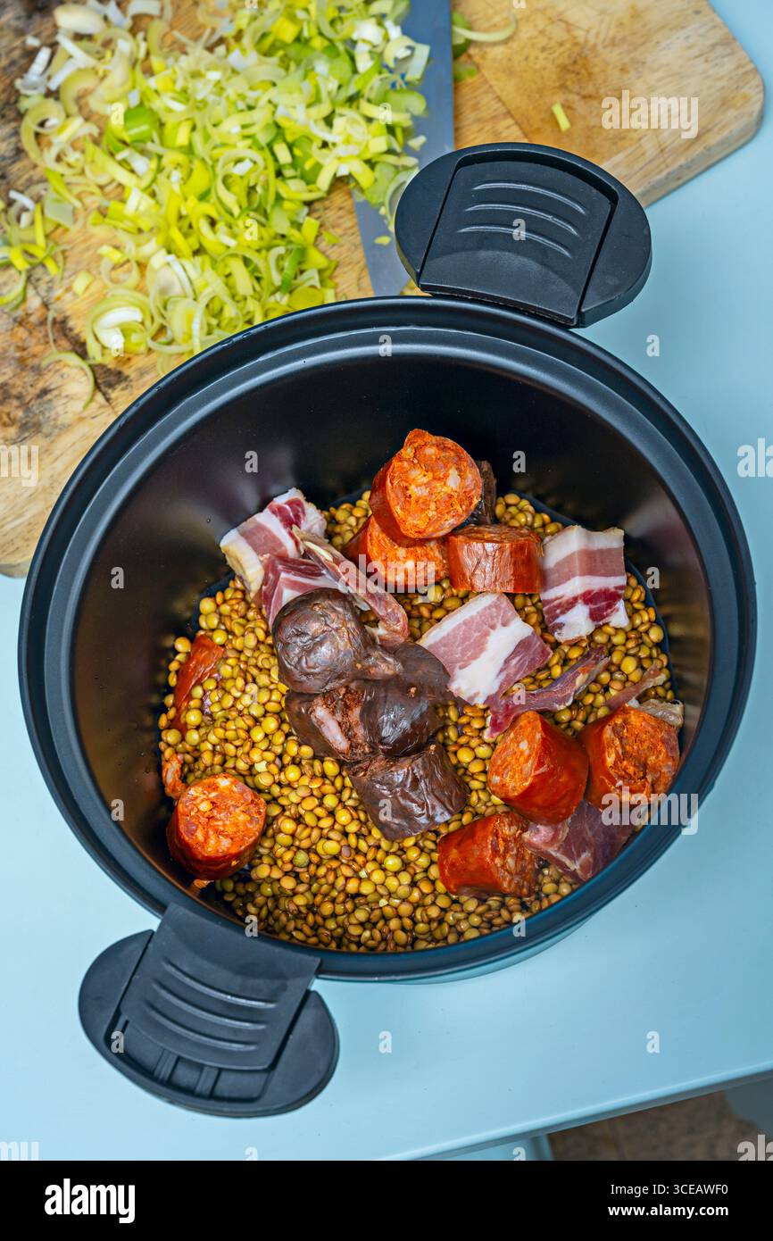 Piatto di lenticchie con chorizo succoso e pancetta croccante, guarnito con uovo sodo tritato per contrasto Foto Stock