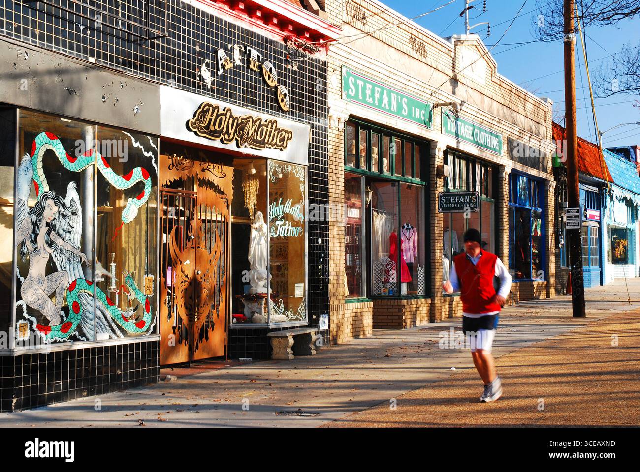 Un uomo adulto fa jogging davanti ai negozi unici e chic del quartiere commerciale Little Five Points di Atlanta Foto Stock