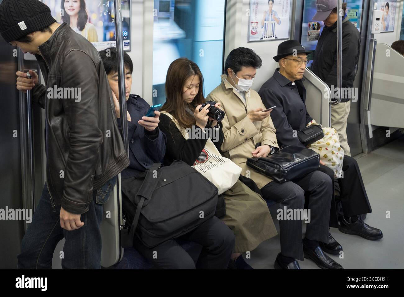 I passeggeri seduti sul sedile unico in Oriente Giappone Azienda ferroviaria linea Yamanote automotrice, Shibuya, Tokyo, Kantō, Honshu, Giappone Foto Stock