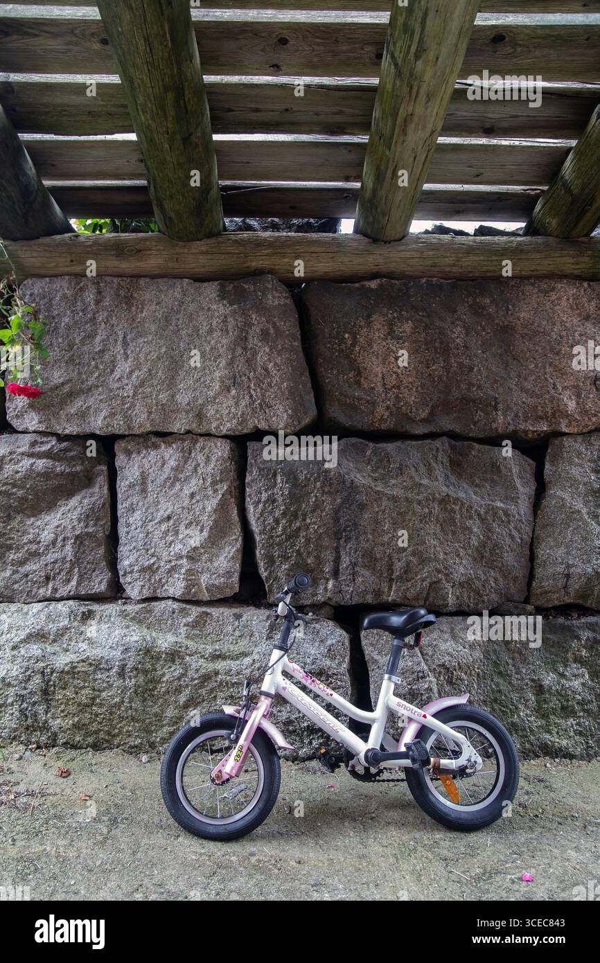 Piccola bicicletta per bambini a due ruote parcheggiata sotto un vecchio ponte di legno. Foto: Bo Arrhed Foto Stock