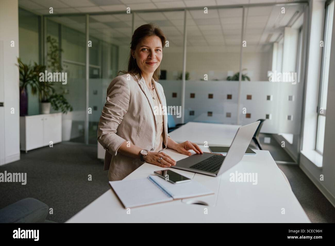 Una donna professionista impegnata nel suo lavoro all'interno di un ambiente d'ufficio moderno Foto Stock