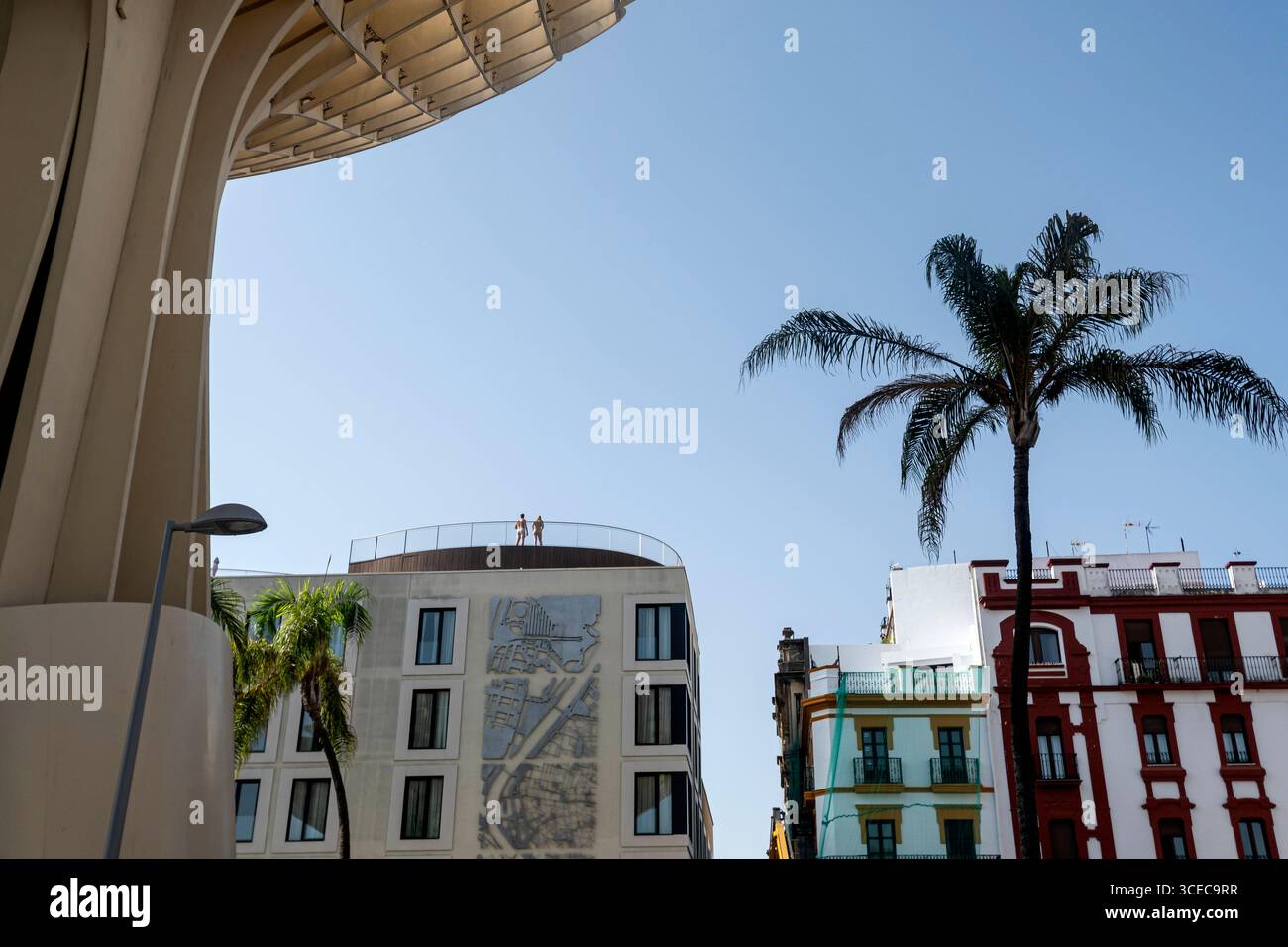 Giovane coppia in costume da bagno sulla terrazza di un hotel moderno vista da Plaza de la Encarnación - Parasol Las Setas, Siviglia, Andalusia, Spagna Foto Stock
