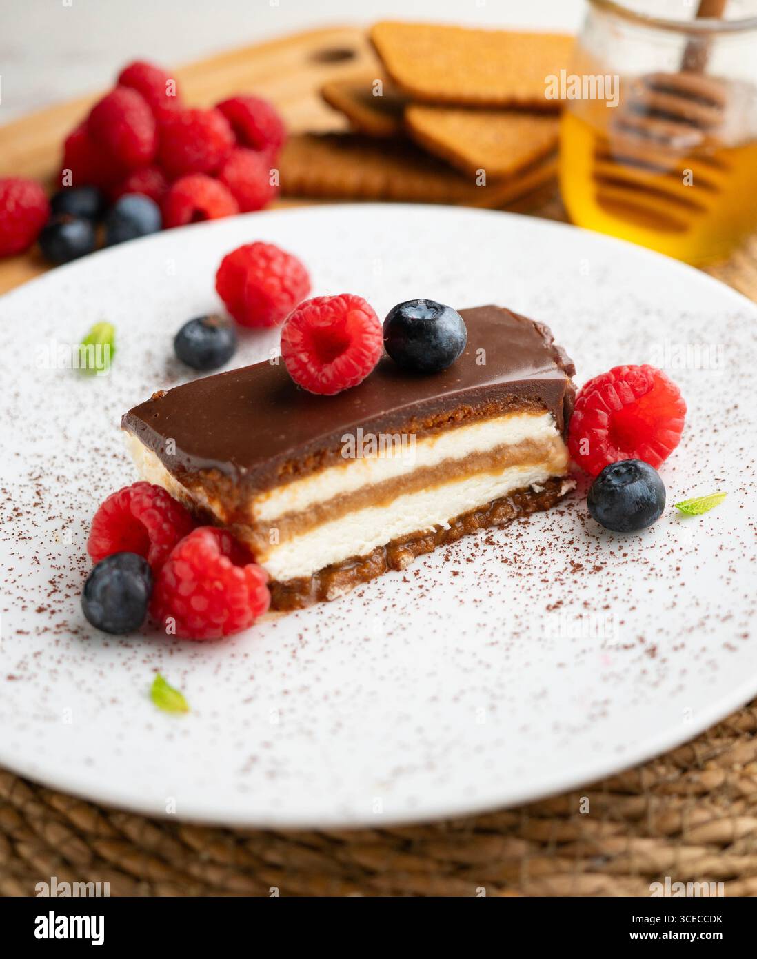 Torta con panna di loto e biscotti con una salsa di cioccolato e frutti rossi. Foto Stock