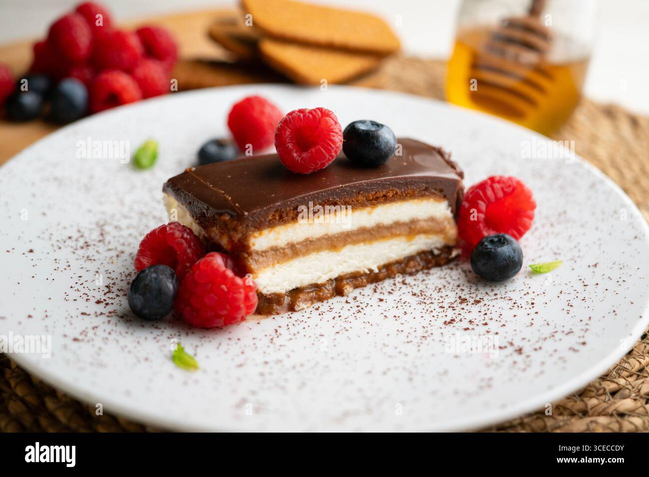 Torta con panna di loto e biscotti con una salsa di cioccolato e frutti rossi. Foto Stock