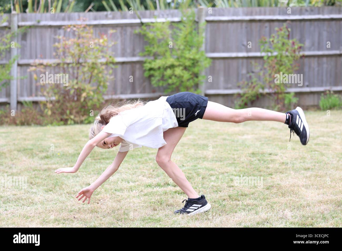 Ragazza che fa il cartwheel in giardino Foto Stock