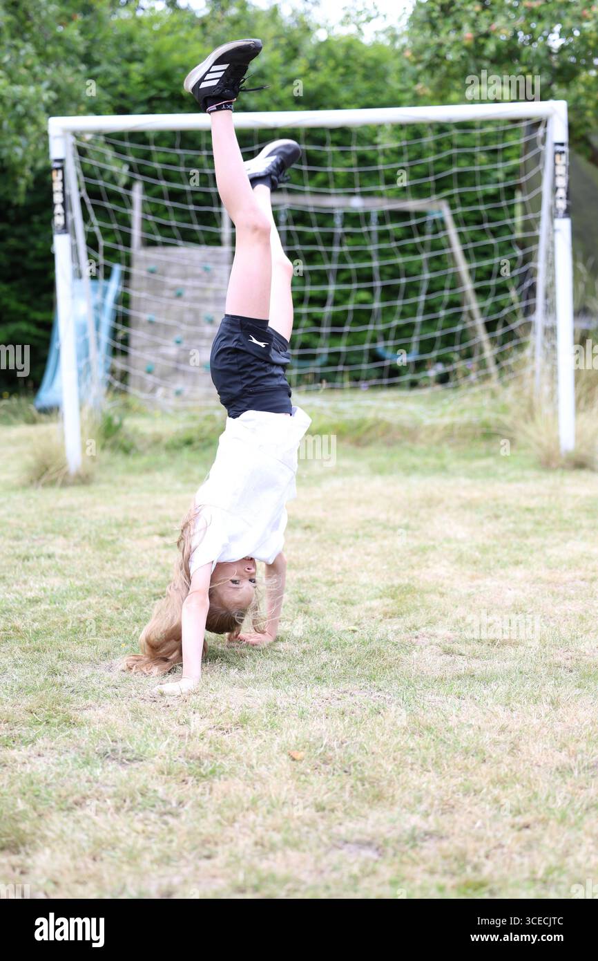 Ragazza che fa il cartwheel in giardino Foto Stock