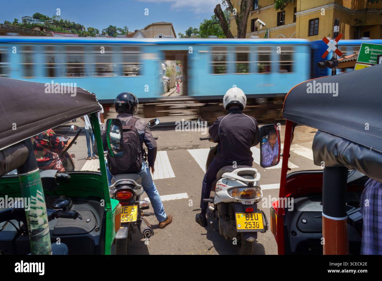 Traffico urbano con tuk tuk, moto e treno a Kandy, Sri Lanka Foto Stock