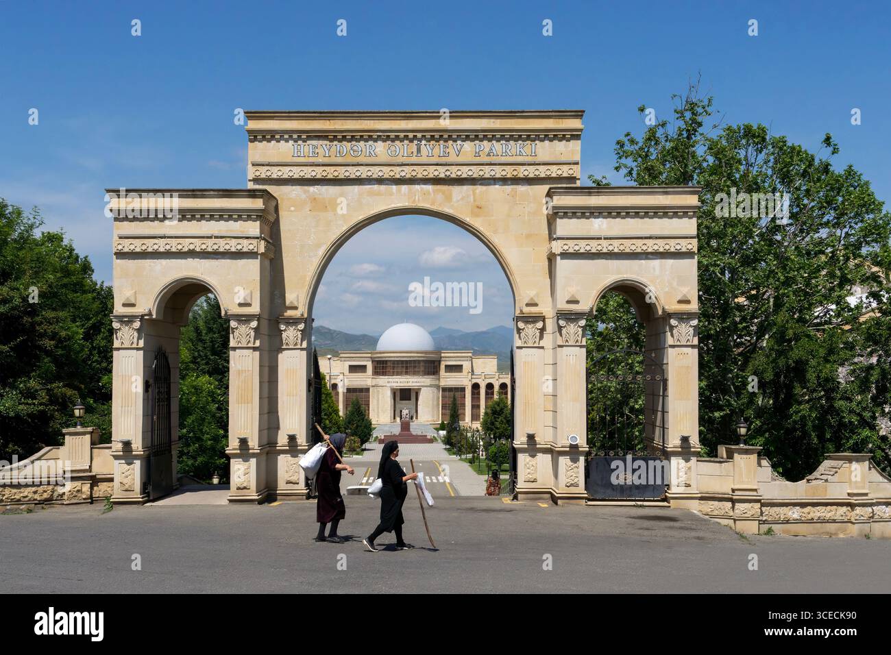 Porta monumentale al Parco Heydar Aliyev con due donne locali che camminano nella città tedesca di Goygol, ora nota come Helenendorf ad Azaerbaijan Foto Stock