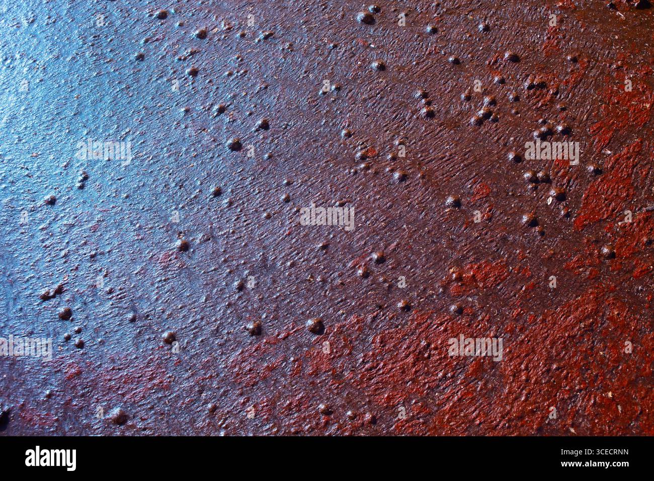 Primo piano di una superficie metallica arrugginita che mostra agenti atmosferici naturali. La texture mostra una gamma di colori terrosi con macchie snocciolate, conferendole un aspetto industriale Foto Stock