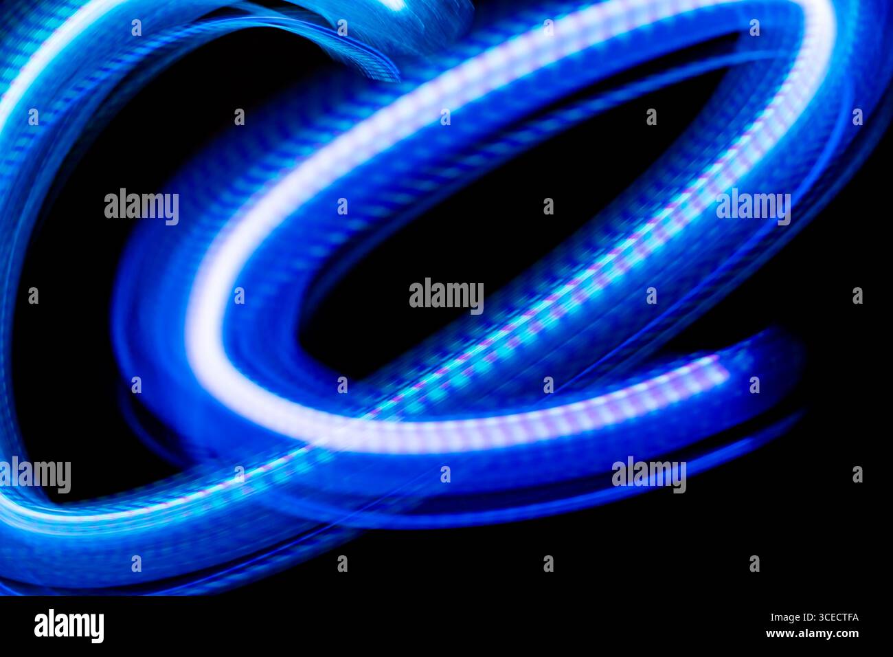 Un'immagine accattivante della luce blu che scorre su uno sfondo scuro, creata utilizzando tecniche fotografiche a lunga esposizione per creare un senso di d Foto Stock