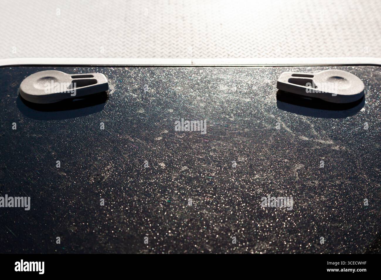 Portello quadrato con vetro di plastica nero sul ponte bianco di uno yacht a vela. Foto Stock