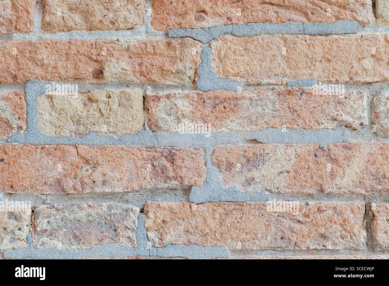 Vista ravvicinata di una parete in mattoni con superfici ruvide prominenti. I mattoni presentano una qualità tattile naturale e un aspetto robusto. Foto Stock