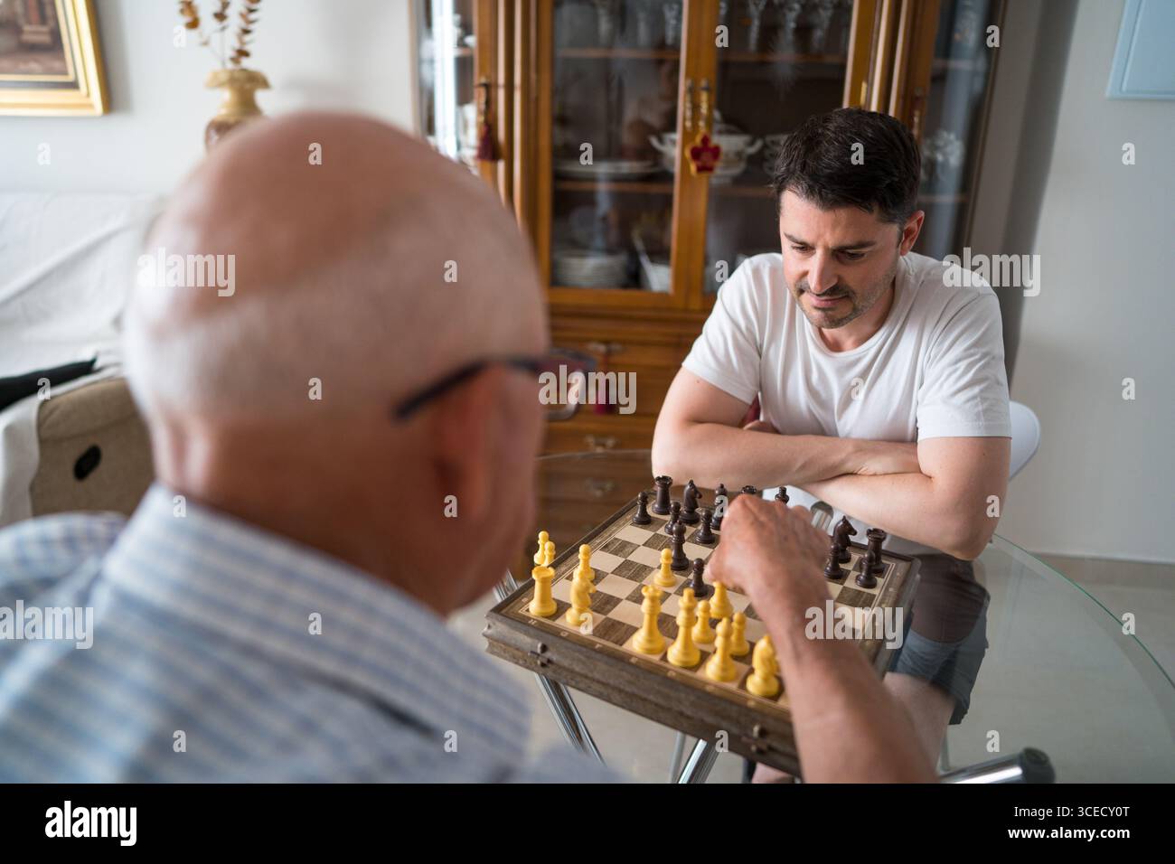 Vista posteriore del padre e del figlio adulto irriconoscibili, partecipa a una partita amichevole a casa, favorendo una connessione attraverso il legame intergenerazionale Foto Stock