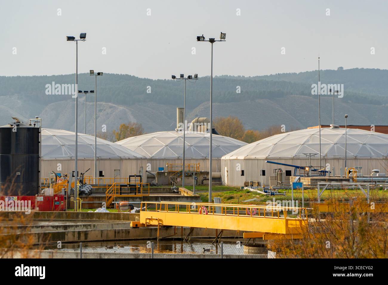 Vista di un impianto di trattamento delle acque reflue a Velilla de San Antonio, Madrid, con chiarificatori a cupola e serbatoi di aerazione. Varie condotte industriali e. Foto Stock