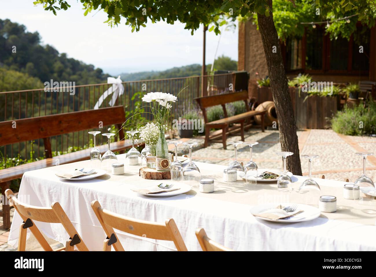 Elegante tavolo da sposa all'aperto adornato con decorazioni floreali bianche in vasi di vetro su un tavolo di legno. Con vista panoramica, la configurazione è entrambe rom Foto Stock