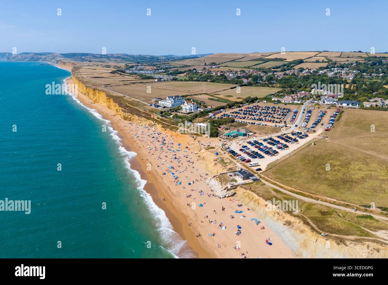 Burton Bradstock, Dorset, Regno Unito. 17 agosto 2025. Meteo nel Regno Unito. La spiaggia e il parcheggio sono pieni di turisti che si godono il caldo sole e il cielo azzurro dell'Hive Beach a Burton Bradstock, sulla Dorset Jurassic Coast, circondata da campi tormentati dalla siccità, mentre l'ondata di caldo continua durante le vacanze estive. Crediti fotografici: Graham Hunt/Alamy Live News Foto Stock