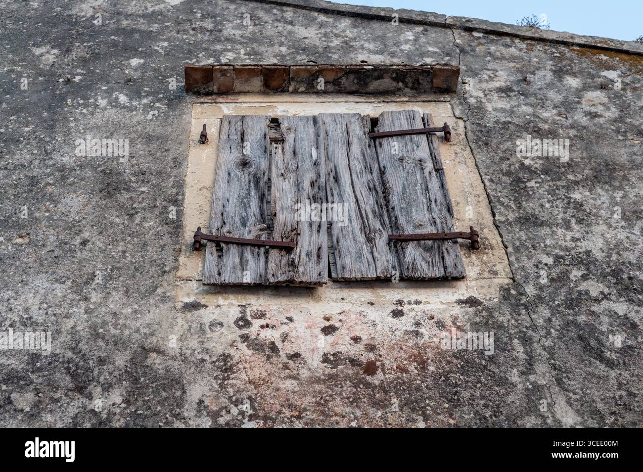 Tende in legno intemperie su un vecchio muro di pietra Foto Stock