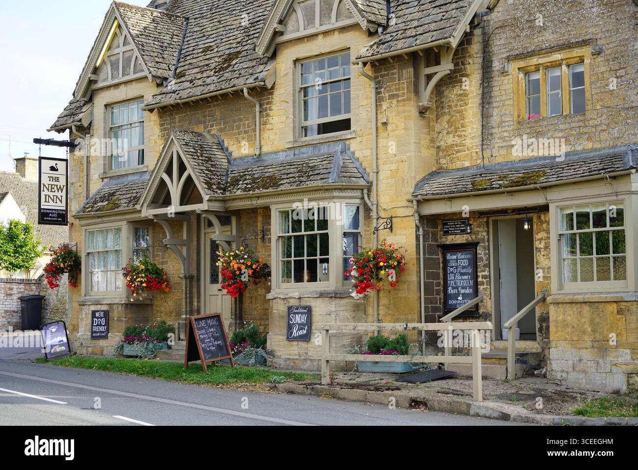 Affascinante pub inglese con cesti di fiori appesi in un giorno di sole. Willersey, Inghilterra Foto Stock