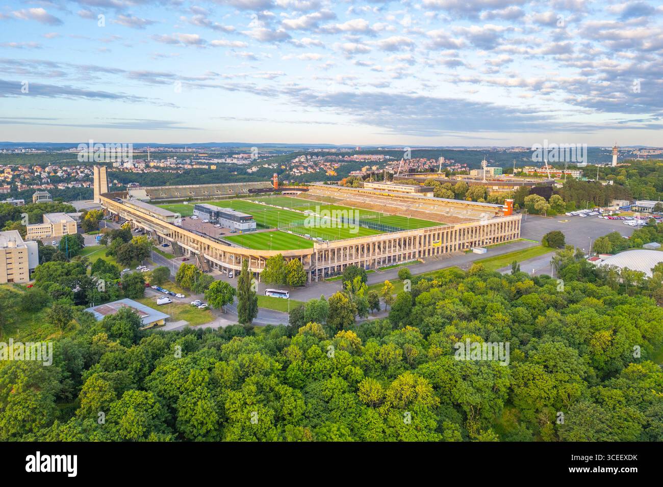 Lo Stadio Great Strahov, situato a Praga, presenta il suo vasto campo aperto in mezzo a una vegetazione lussureggiante. Le colline circostanti e i paesaggi urbani si aggiungono alle impressionanti vedute dello stadio durante la luce del tardo pomeriggio. Foto Stock