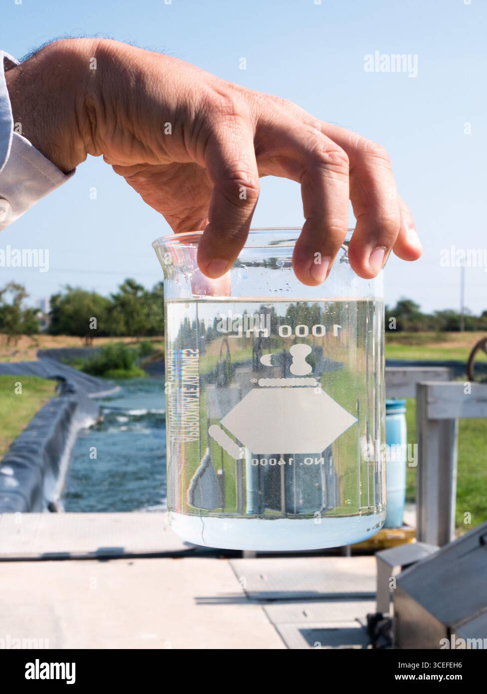 Mano di un uomo che maneggia un campione di acqua trattata in un impianto di trattamento delle acque reflue in Messico Foto Stock