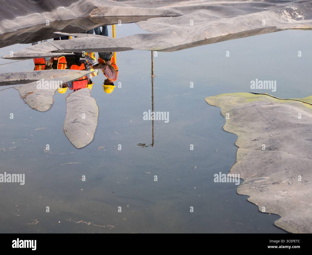 Riflessione in uno stagno d'acqua di un gruppo di ingegneri durante un tour in un impianto di trattamento delle acque reflue in Messico Foto Stock