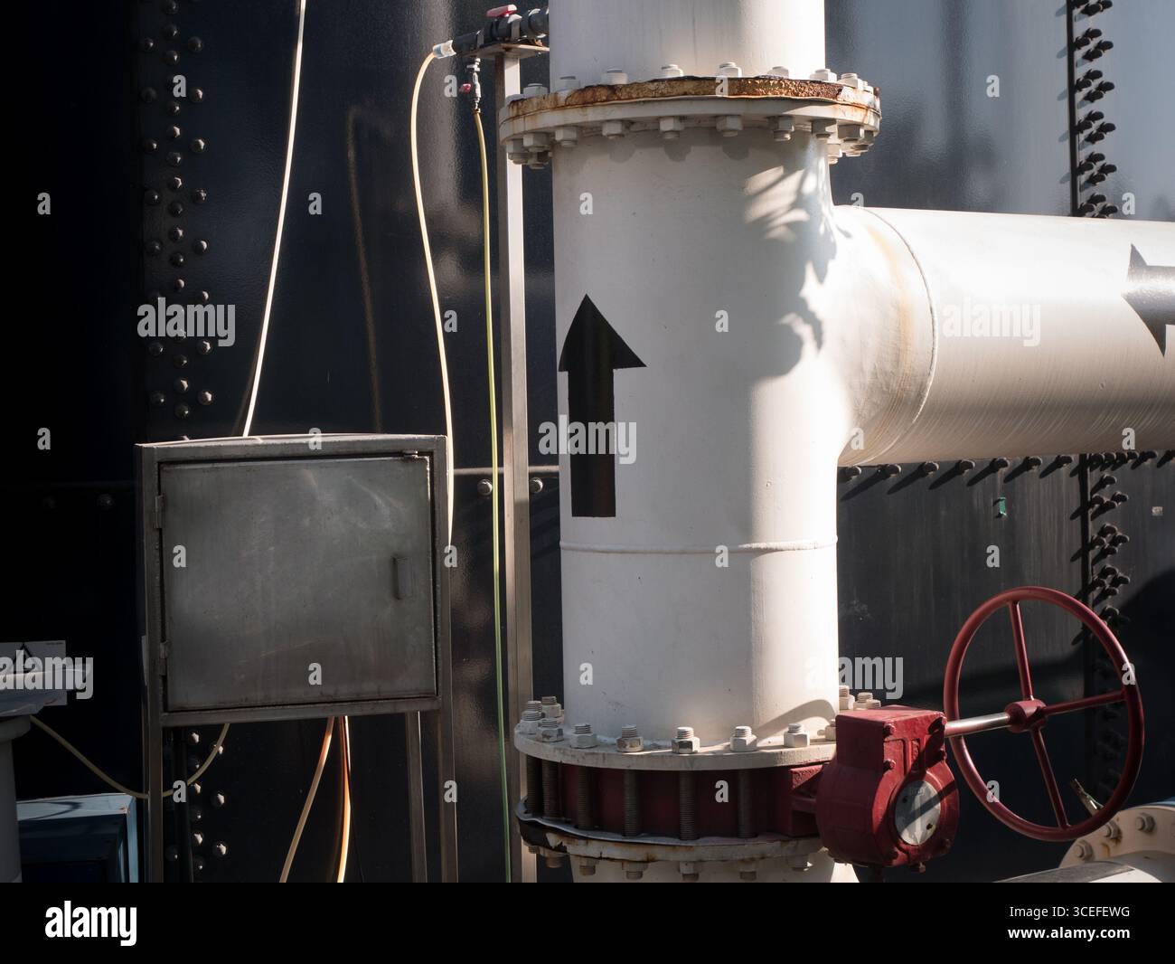 Frecce che mostrano la direzione del flusso in una conduttura accanto a un serbatoio in un impianto di trattamento delle acque reflue in Messico Foto Stock