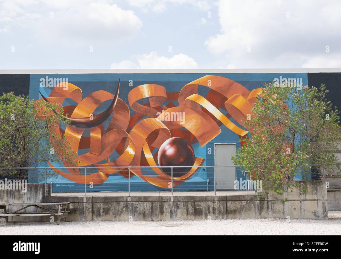 Murale di un nastro dorato con palla e corna su sfondo blu. Dipinto da Abraham Burciaga in Art Alley a Sawyer Yards a Houston, Texas. Foto Stock