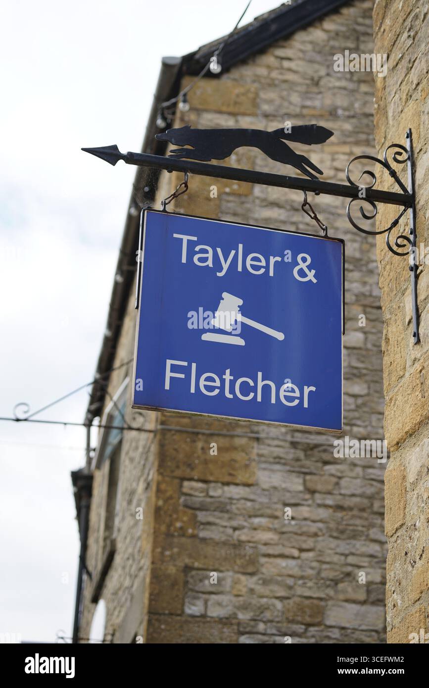 Cartello in metallo di Tayler e Fletcher contro il muro di pietra all'aperto. Stivaggio-on-the-Wold, Inghilterra Foto Stock