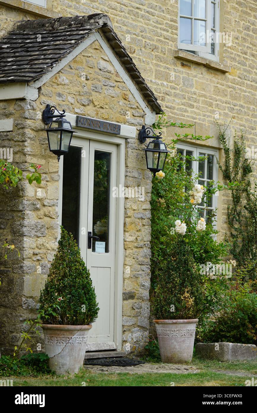 Ingresso al rustico cottage in pietra con piante decorative e porta in legno. Churchill, Inghilterra Foto Stock