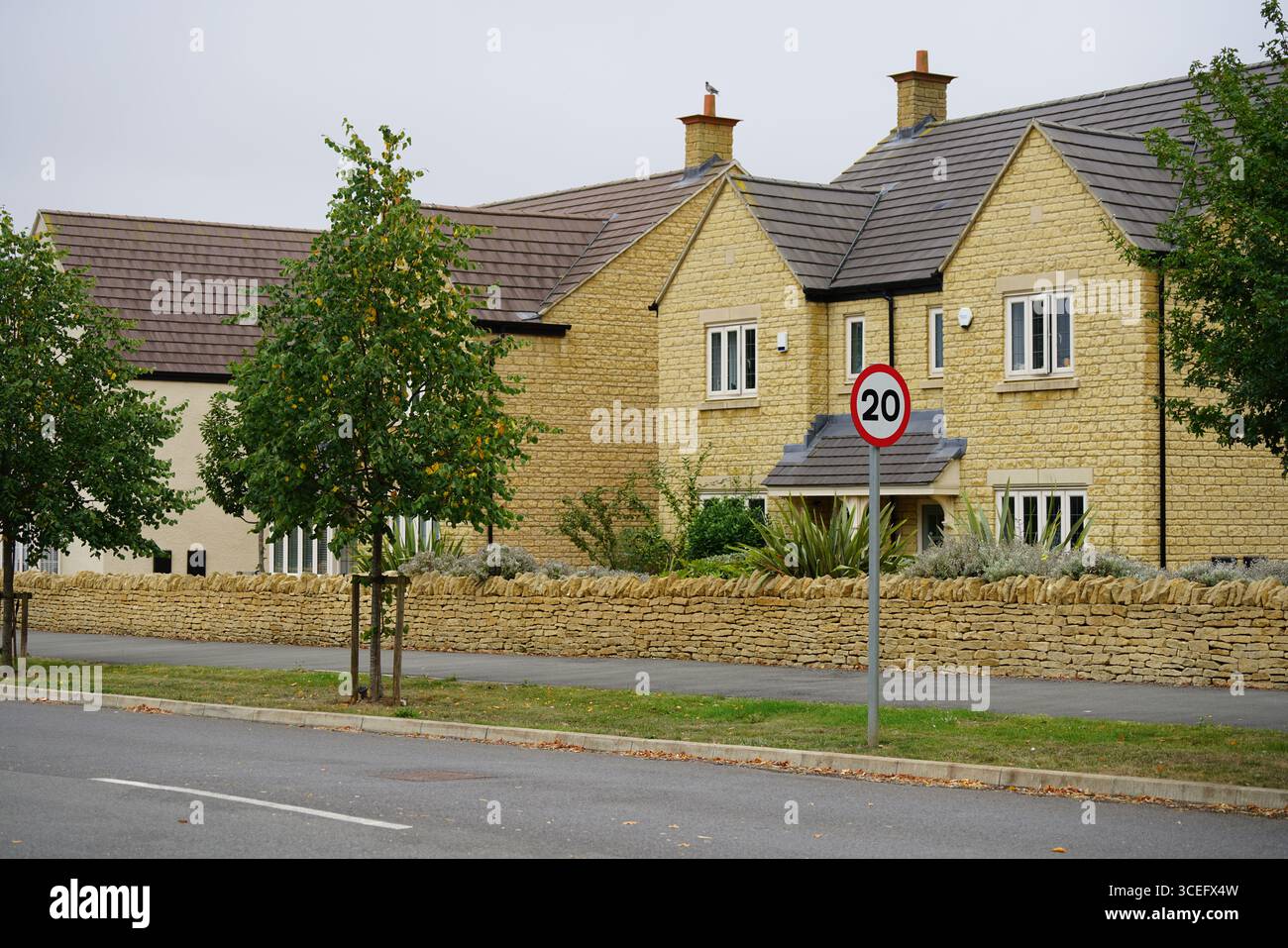 Casa tradizionale in pietra con cartello Speed Limit nel quartiere residenziale. Chipping Norton, Inghilterra Foto Stock