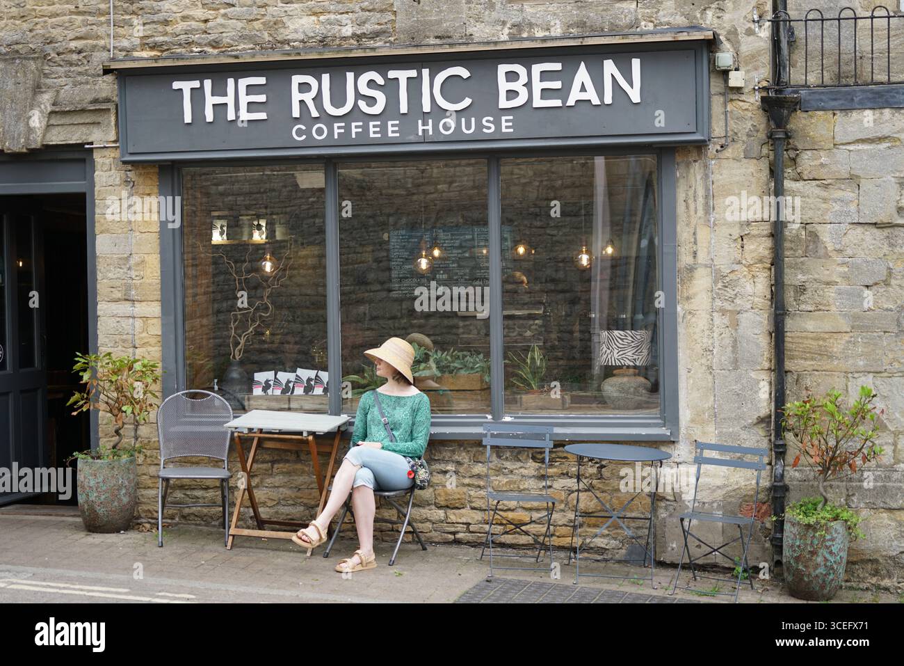 Affascinante rustico Coffee House esterno con donna seduta che gode dell'atmosfera. Chipping Norton, Inghilterra Foto Stock